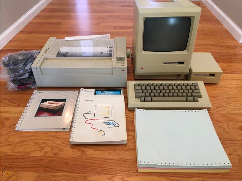 A computer sitting on top of a wooden table Description automatically generated